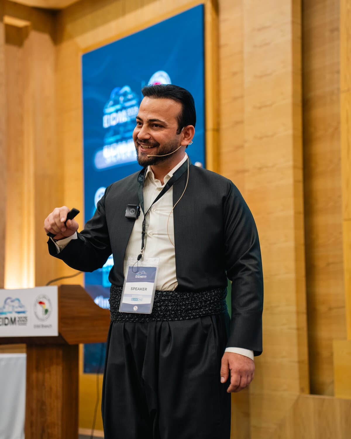 Dr. Jegr Koyi smiling at the podium as an invited speaker at a dental conference